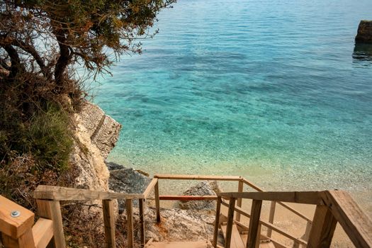 Discover the stunning turquoise waters and serene beach of Zakynthos from these rustic wooden stairs.