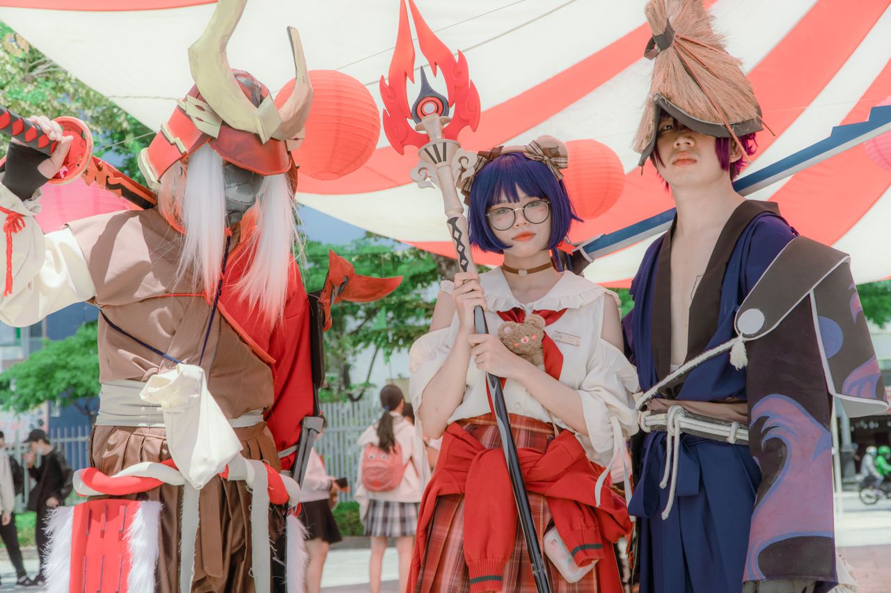 three cosplayers dressed as fantasy characters pose together under vib