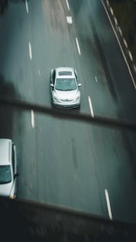 通过空中拍摄，捕捉汽车在多雨的城市道路上移动时产生的运动模糊效果
