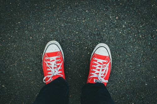 Free Close-up of red sneakers on asphalt, showcasing casual footwear style. Stock Photo