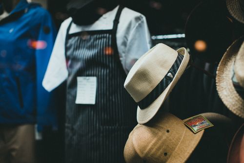 Free Close-up of fashionable fedora hats and aprons in a stylish boutique window display. Stock Photo