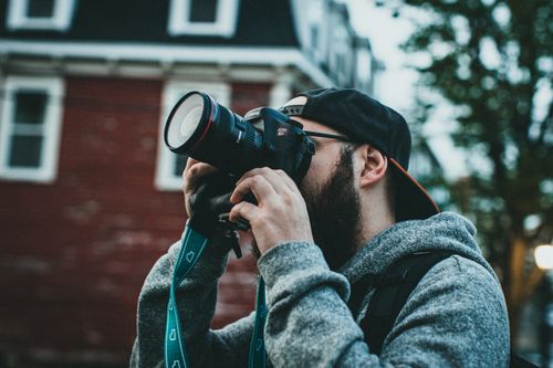 Free A bearded man photographer capturing a scene outdoors with a DSLR camera. Stock Photo