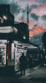 在戏剧性的天空下，繁忙的城市街道旁，热闹的报摊与迷人的黄昏构成了一幅生动的场景