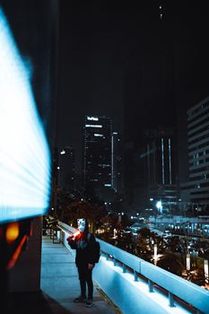 A masked figure stands against the illuminated cityscape of Jakarta at night, exuding mystery.