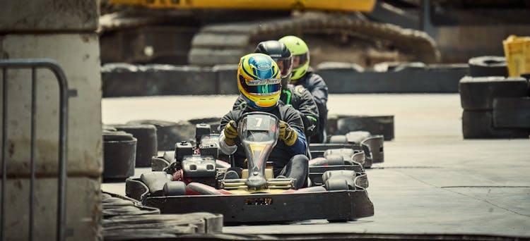 People Wearing Helmets Riding Go-karts