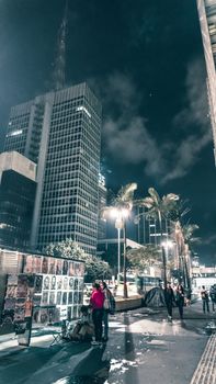夜幕下的城市在阴云密布的天空下依然充满活力，摩天大楼、街头小贩和棕榈树点缀其间