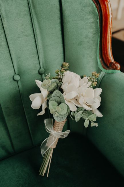 A close-up view of a beautiful white flower bouquet resting on a vintage green armchair.