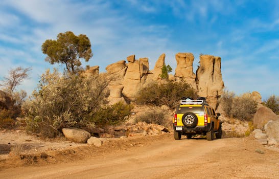 Yellow SUV exploring a rugged desert landscape under a clear blue sky.
