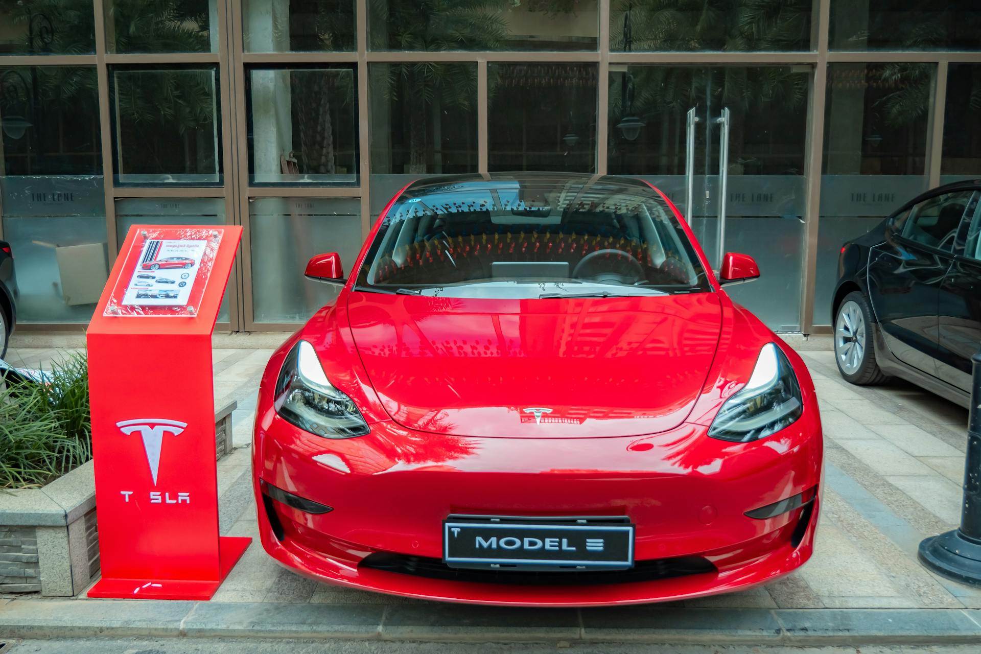 A stylish red Tesla Model 3 parked in an urban area, showcasing its sleek design and luxury features.