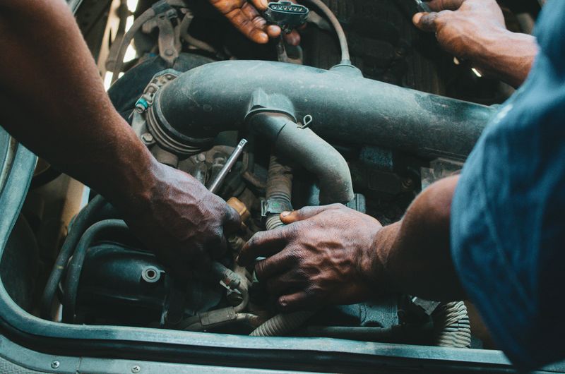 Manos trabajando sobre motor de vehículo