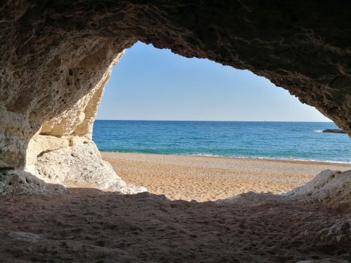 Free Peaceful sandy beach viewed from a seaside cave in Dorset, England. Ideal for nature lovers. Stock Photo