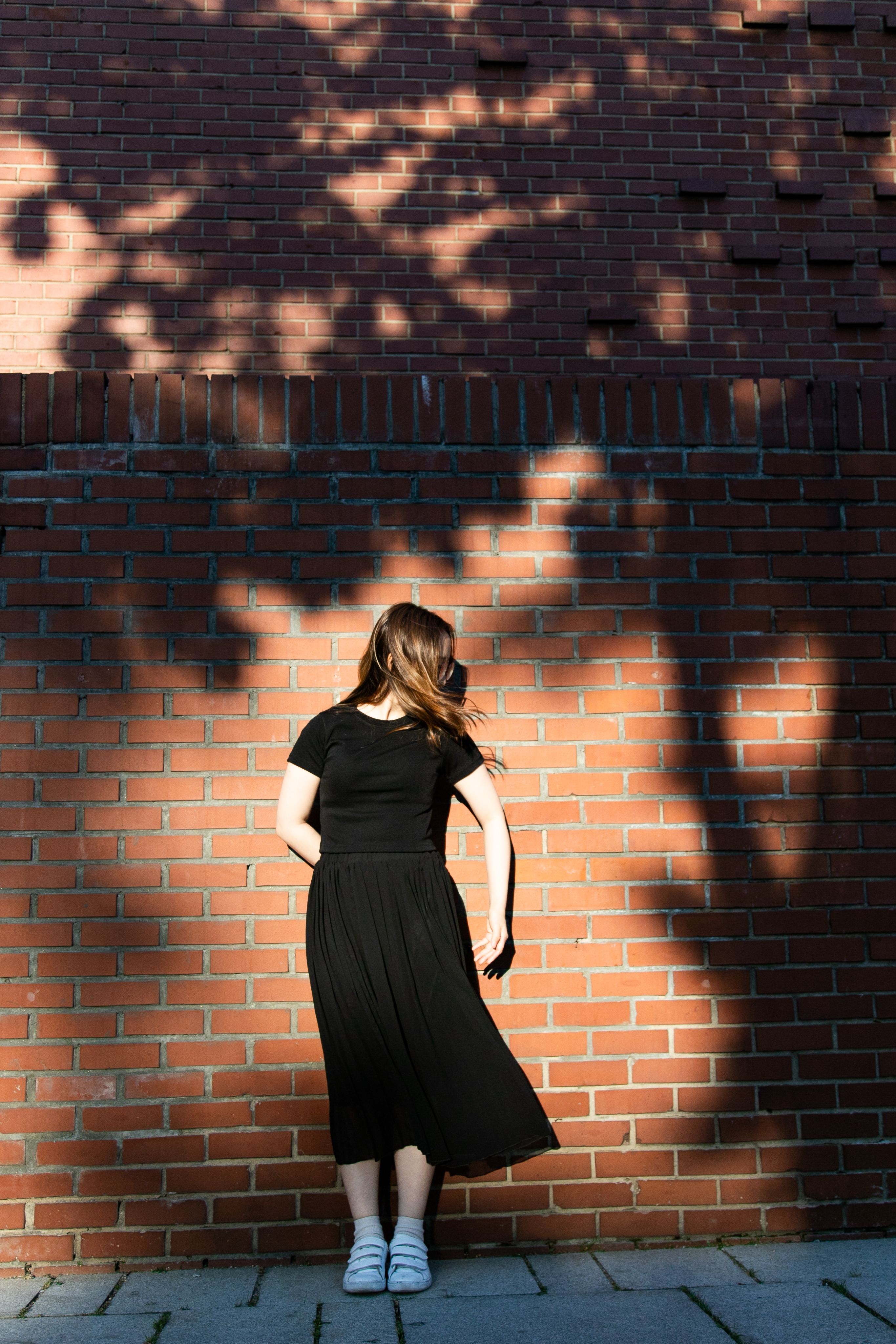 Woman in Black Dress Leaning on Brick Wall · Free Stock Photo