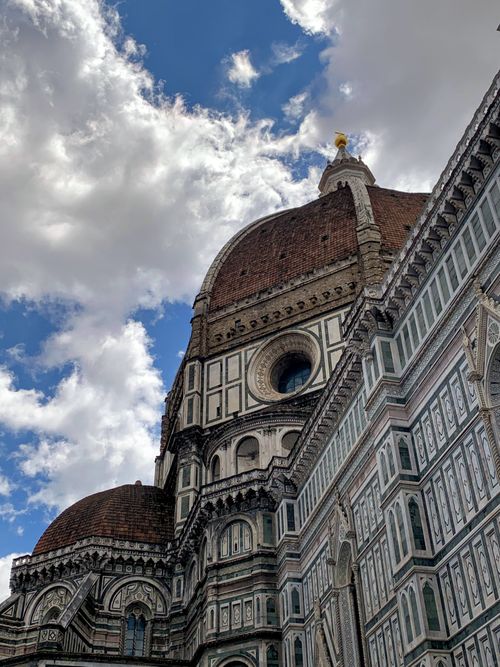 Free Stunning low angle shot of Florence Cathedral's iconic dome against a blue sky with clouds. Stock Photo