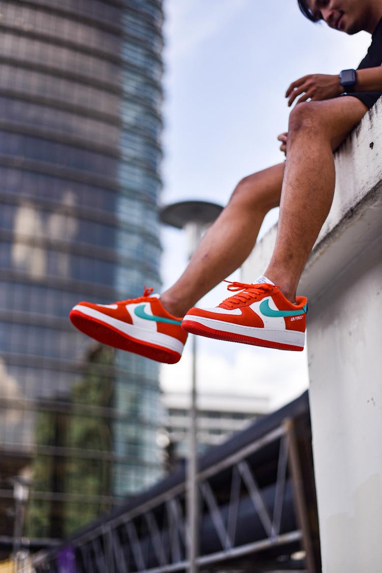 A Person Wearing Nike Air Force 1 Sneakers Sitting On A Ledge