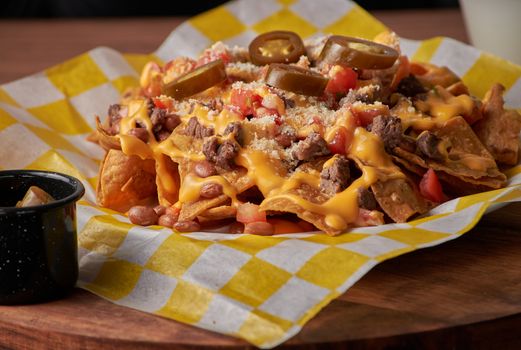 A mouthwatering nacho platter with cheese, jalapenos, and toppings on checkered paper.
