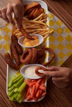Flat lay of assorted fried snacks with dipping sauces on a checkered tablecloth. Perfect for food photography.