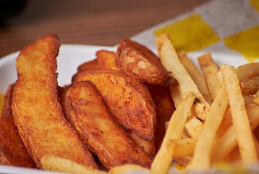 Appetizing close-up of crispy French fries and potato wedges, perfect for fast food lovers.