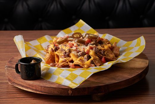 Tempting nachos topped with cheese, jalapenos, and beef on a wooden platter.