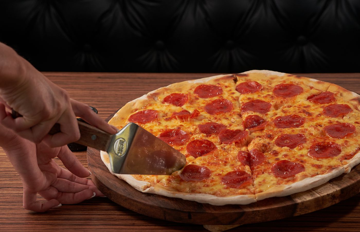 Fresh pepperoni pizza being sliced, highlighting delicious cheese and toppings.