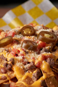 Tasty nachos topped with melted cheese, jalapeños, and diced tomatoes, perfect for a snack.