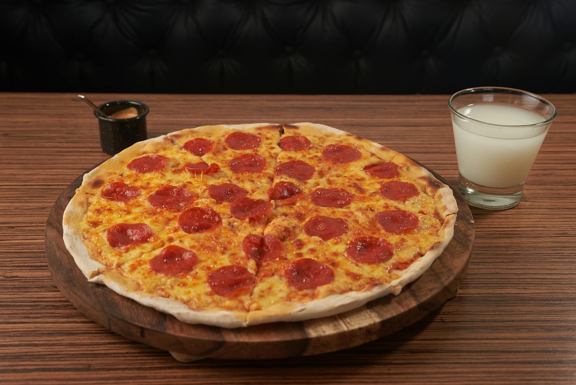 Delicious pepperoni pizza served with a drink on a wooden table.