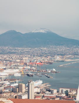 Aerial view of Naples cityscape with Mount Vesuvius in the background under a clear sky.