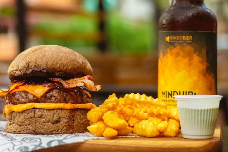 Cheeseburger And Fries On A Cutting Board With A Bottle Of Beer