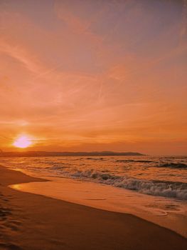 A breathtaking beach scene with waves crashing gently beneath a stunning sunset.