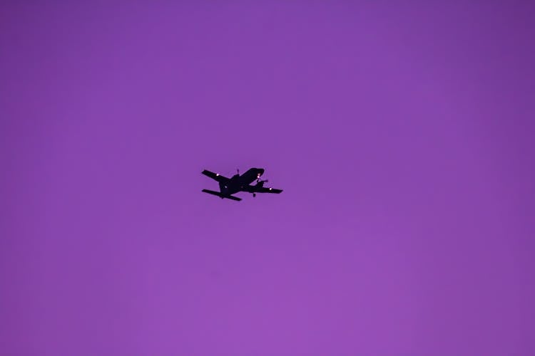 A Flying Airplane In The Purple Sky
