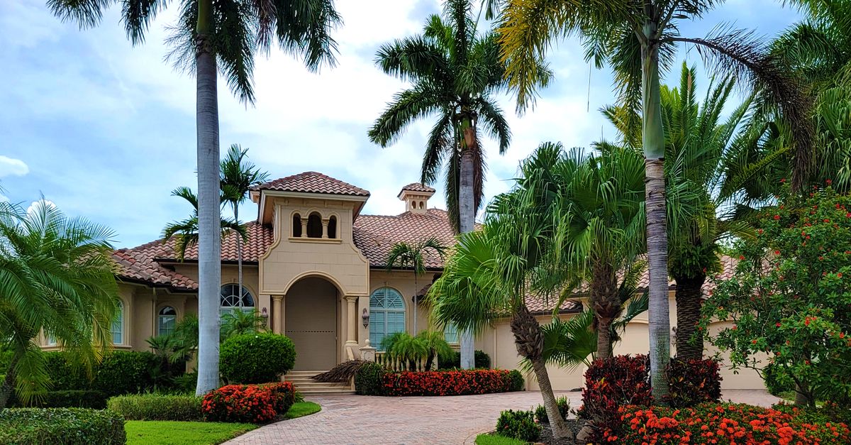 Elegant mansion with lush palm trees and landscaped garden, perfect for luxury living.