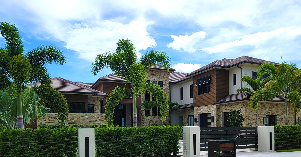 A modern and luxurious house surrounded by lush palm trees, perfect for real estate showcasing.