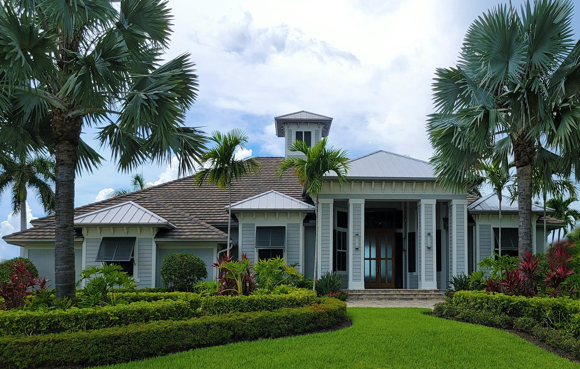 Luxurious modern mansion surrounded by lush greenery and palm trees, ideal for real estate promotion.