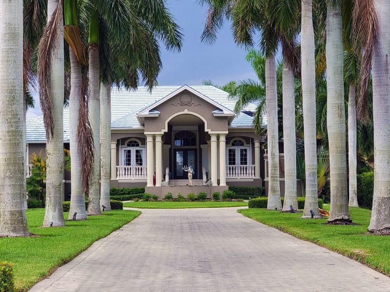 Residential house with palm trees lining the driveway under a clear sky