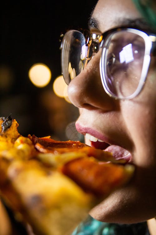 Woman eating pizza with bokeh lights 