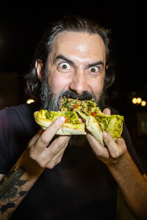 Man eating pesto pizza with eyes opened