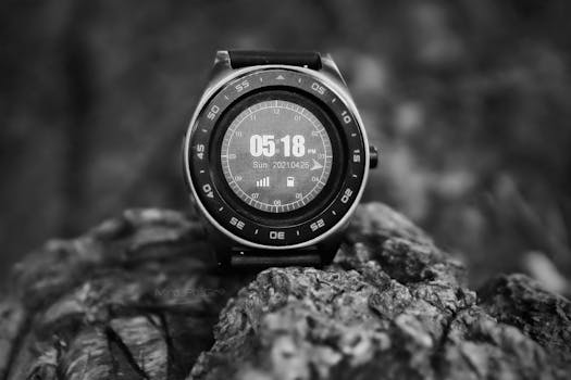 Close-up of a stylish smartwatch in grayscale, showcasing time and date on rocky background.