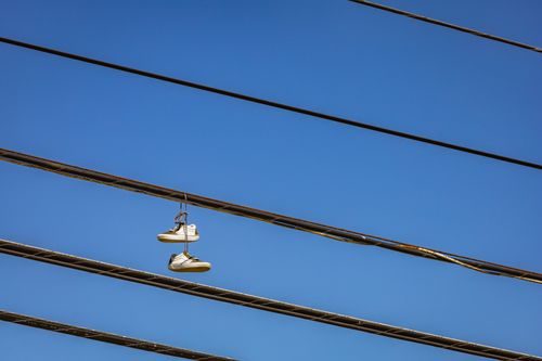 Free Pair of sneakers hanging on electric wires with a clear blue sky background. Stock Photo