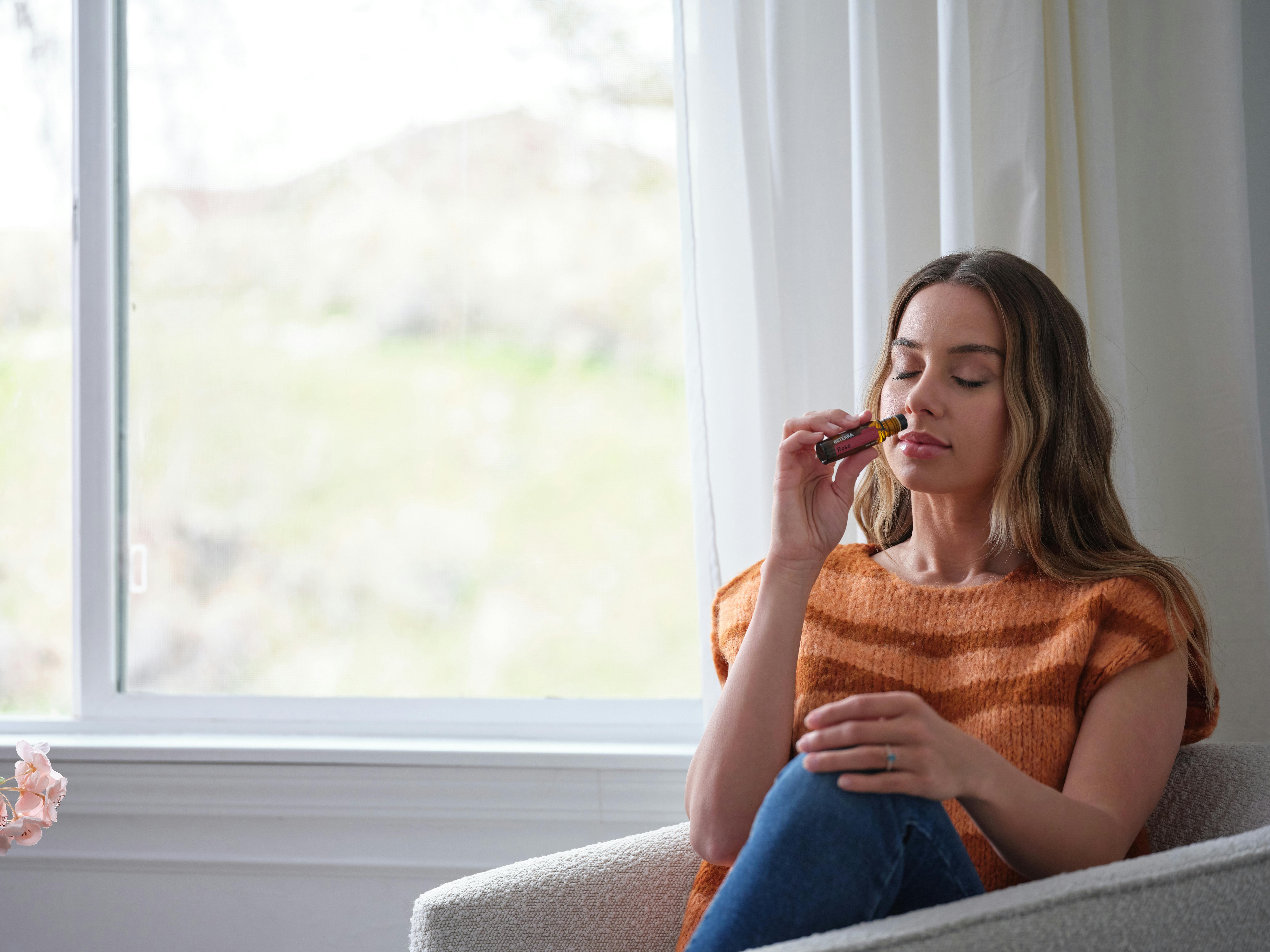 A young woman sitting by the window, relaxing with essential oil aromatherapy.