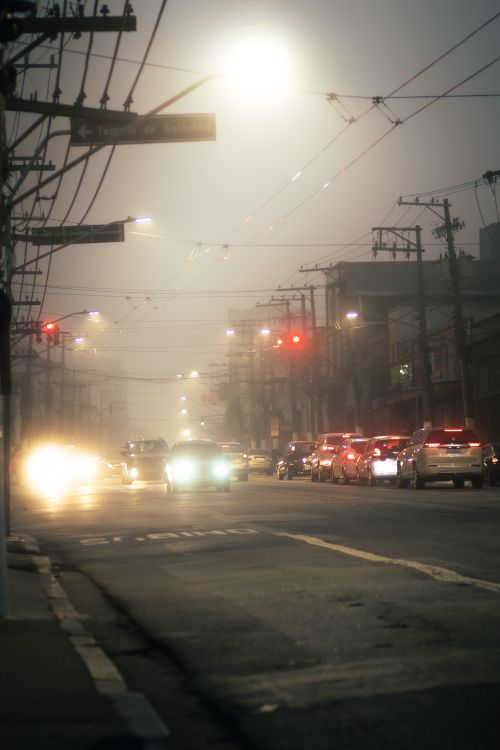 Free Foggy urban street at night with illuminated traffic and city lights creating a moody atmosphere. Stock Photo
