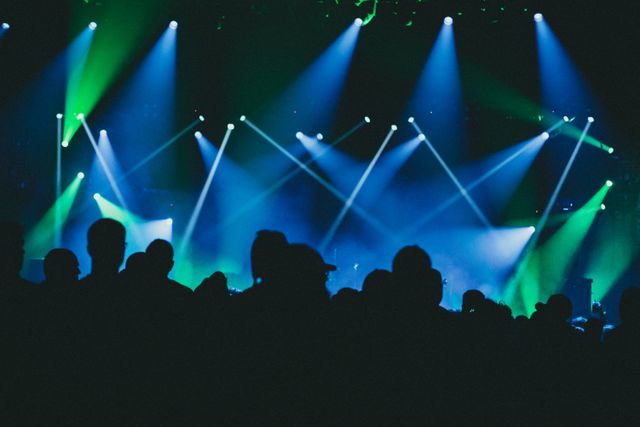 Stage lights over a silhouetted crowd at a live show, Jonathan Cooper on Pexels