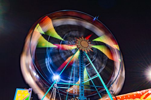 Free Vibrant long exposure shot of a ferris wheel spinning at night in an amusement park. Stock Photo