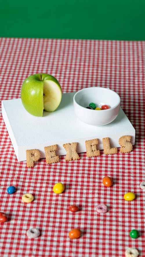 Free Green Apple and Candies on a Checked Tablecloth Stock Photo