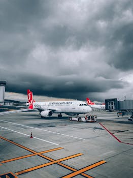 A Turkish Airlines aircraft parked on a runway under a dramatic cloudy sky.