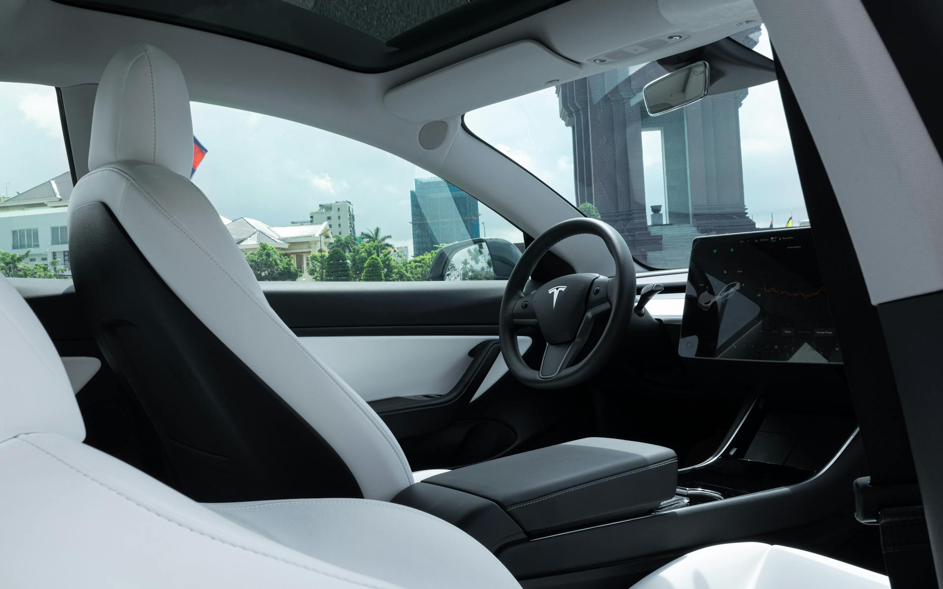 Luxurious interior of a modern electric car with white leather seats and advanced dashboard features.