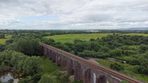 Free Aerial view of an historic railway viaduct amidst lush greenery in the United Kingdom. Stock Photo