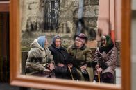 Four elderly women in winter clothes sitting and chatting outdoors in Lviv, Ukraine.