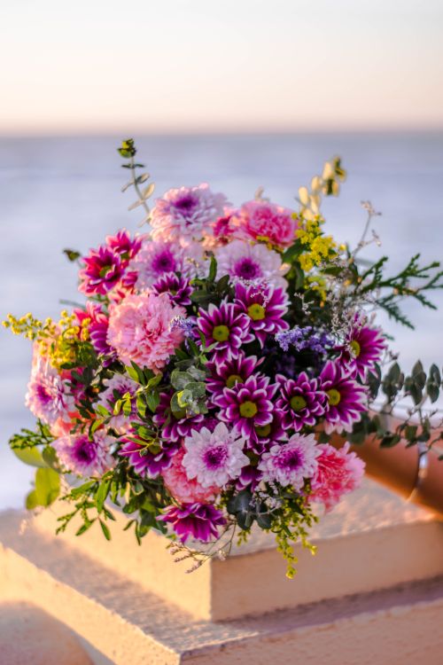 Free Elegant bouquet with colorful flowers against a serene beach backdrop at sunset. Stock Photo