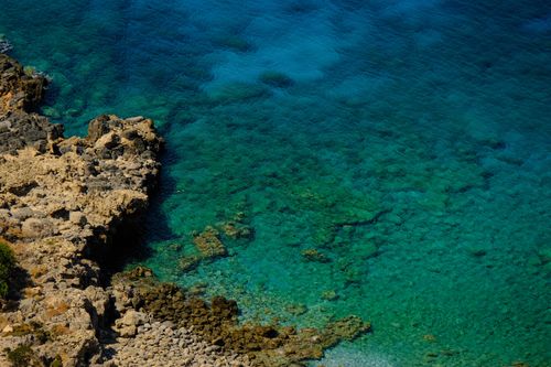 Free Stunning aerial photograph of a rocky coastline with clear blue water, showcasing vibrant natural beauty. Stock Photo