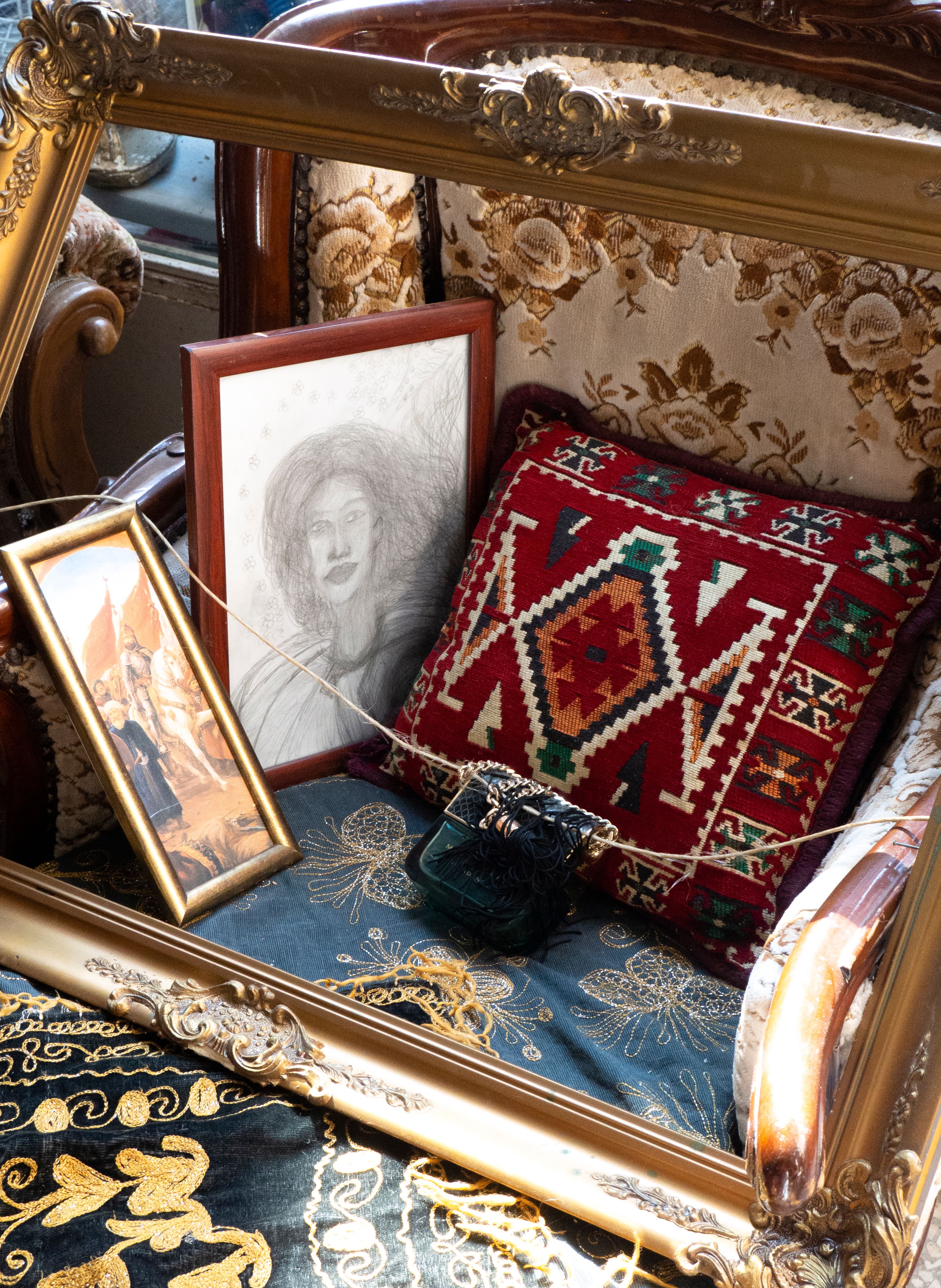 Antique-style armchair with framed art and a patterned pillow in an Istanbul store.