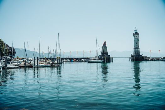 Tranquil scene of Lindau harbor with iconic lighthouse and boats on Lake Constance.